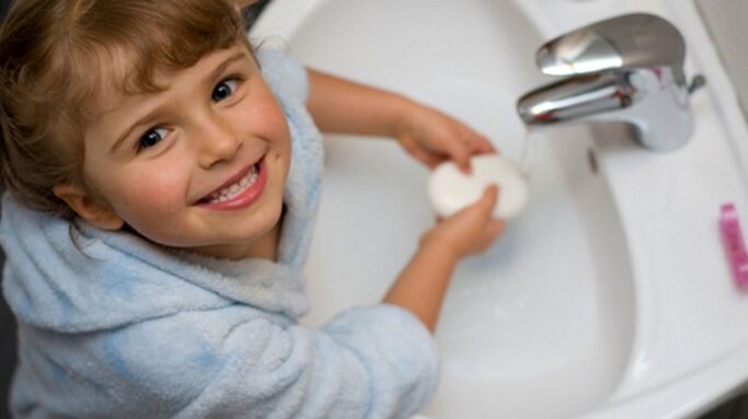 a gyermek szappannal mossa meg a kezét, hogy megakadályozza a férgeket